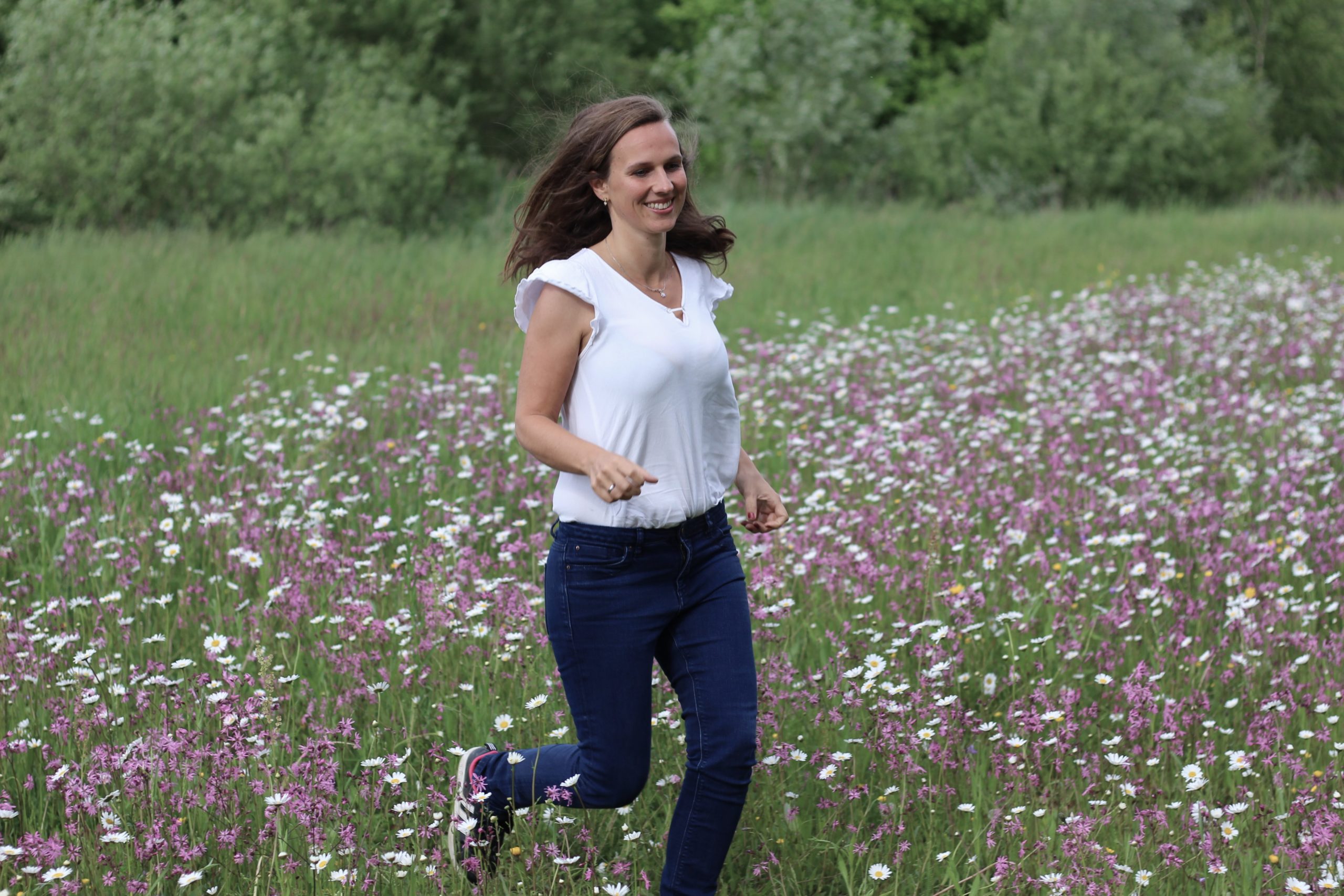 Frau läuft über eine Blumenwiese, sie freut sich ein Coaching für Frauen in München absolviert zu haben.