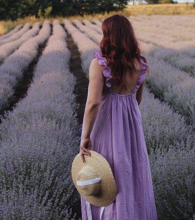 Anja.Jungbeck.Life-CoachingfürFrauen.München Eine Frau steht mit lila Kleid in einem Lavendelfeld und möchte gerne ihre Berufung durch ein Coaching für Frauen München finden.