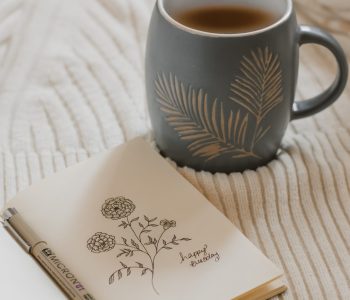 Auf dem Bild ist ein Buch mit einer Zeichnung und einer Tasse Kaffee zu sehen.